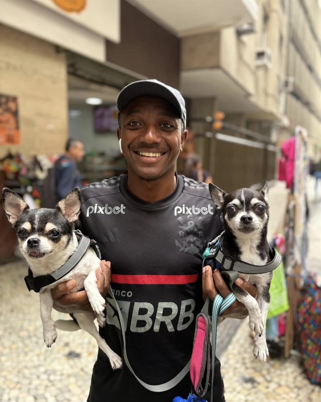 Breno sorrindo com dois chihuahuas no colo, Axel e seu companheiro